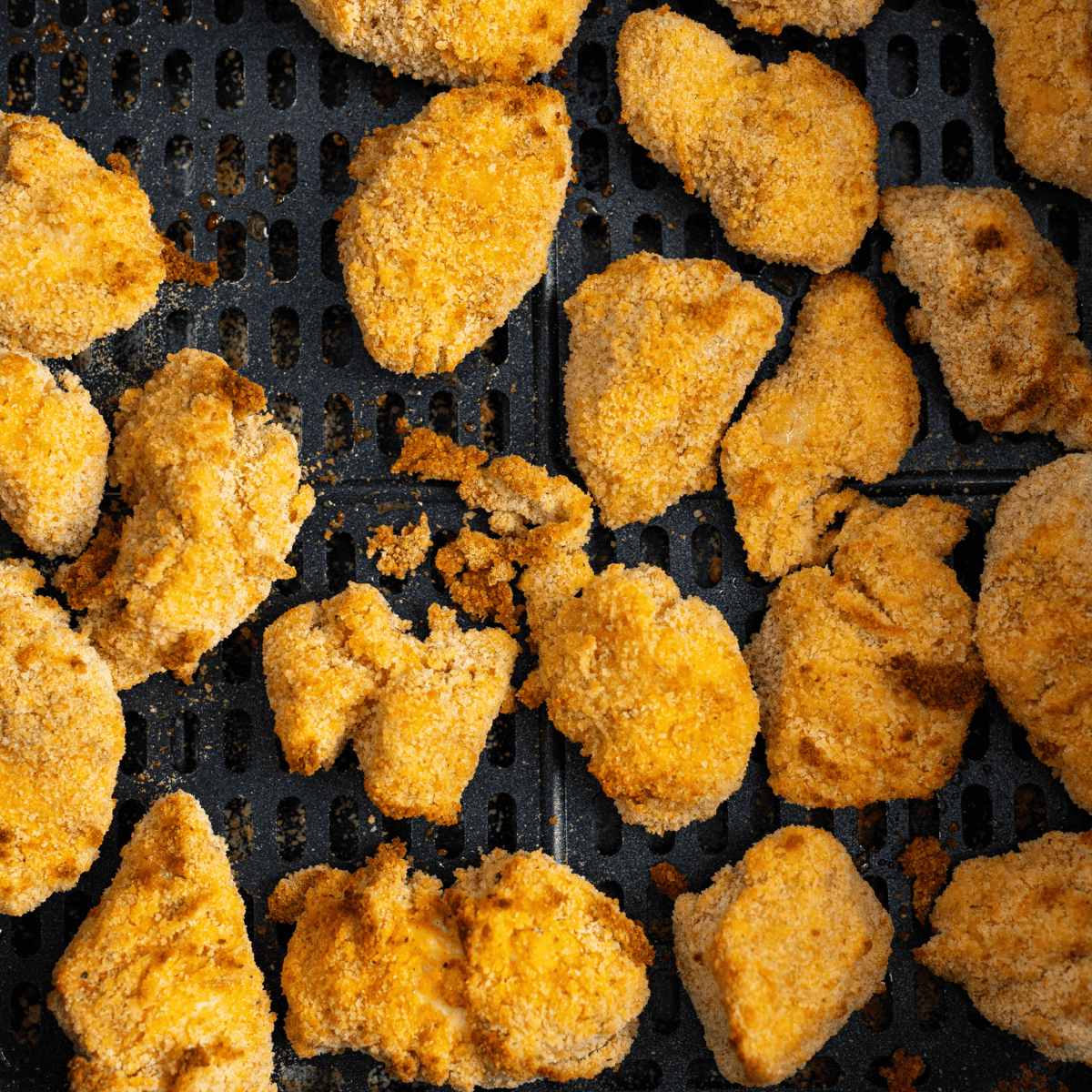Golden crispy air fryer karaage cooking in a single layer inside the air fryer basket with crackled coating edges