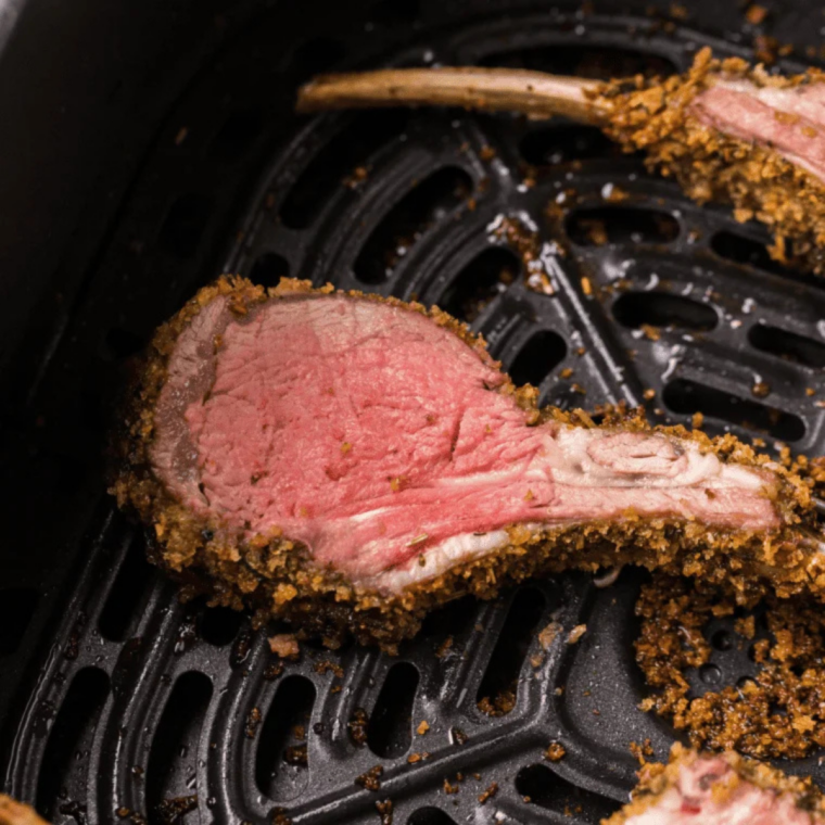 Seasoned lamb cutlets spaced in a single layer in the air fryer basket