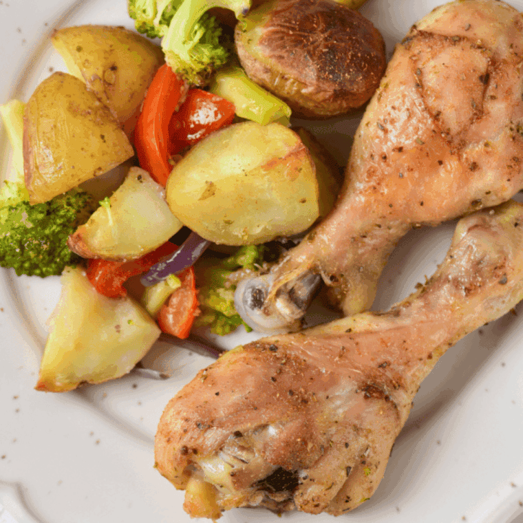 Air fryer chicken drumsticks with colorful vegetables on a plate, golden and cooked to perfection.