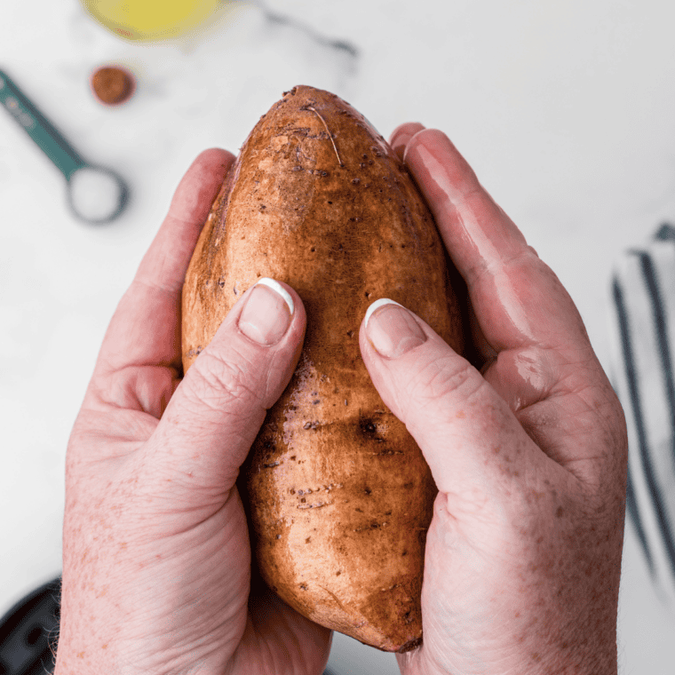 Sweet potato rubbed with olive oil and wrapped in aluminum foil on a parchment-lined baking sheet
