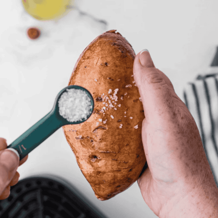 Raw sweet potato being rubbed with olive oil before going into the air fryer basket