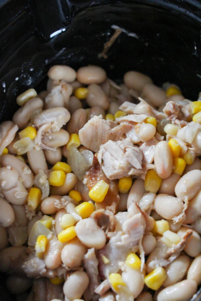 White beans, green chiles, and salsa verde layered over browned turkey in a slow cooker insert