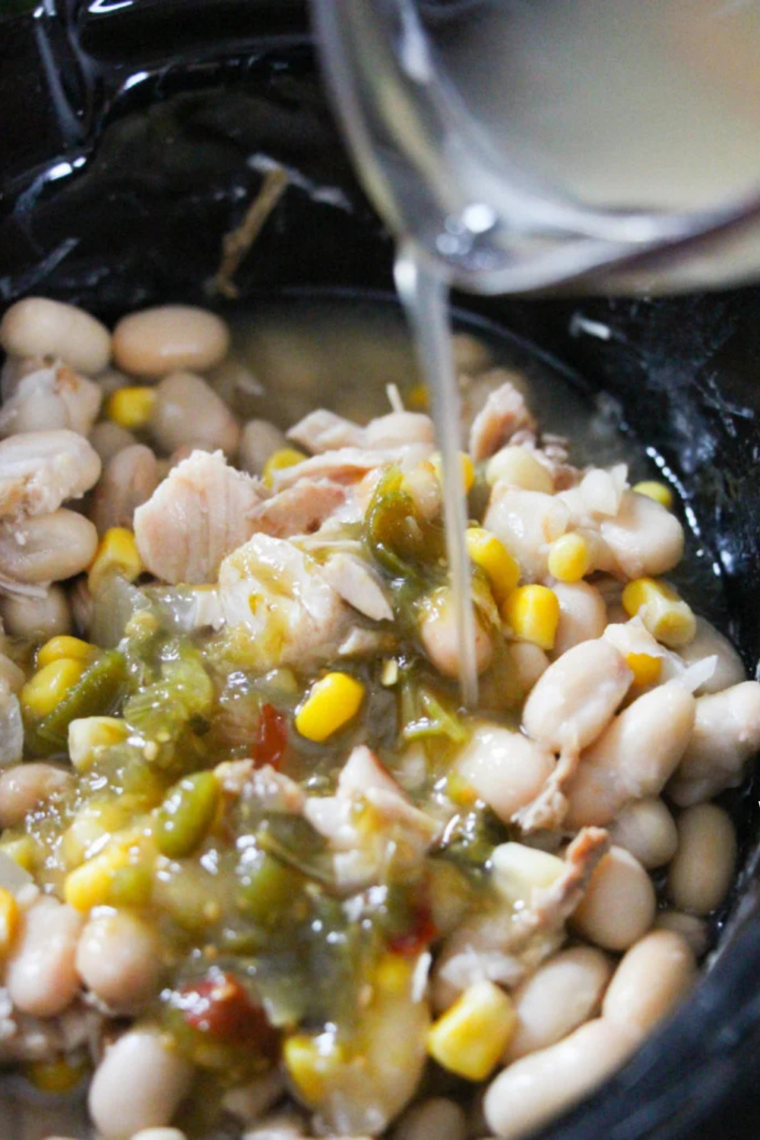 Browned turkey, white beans, green chiles, and salsa verde layered in a slow cooker before cooking