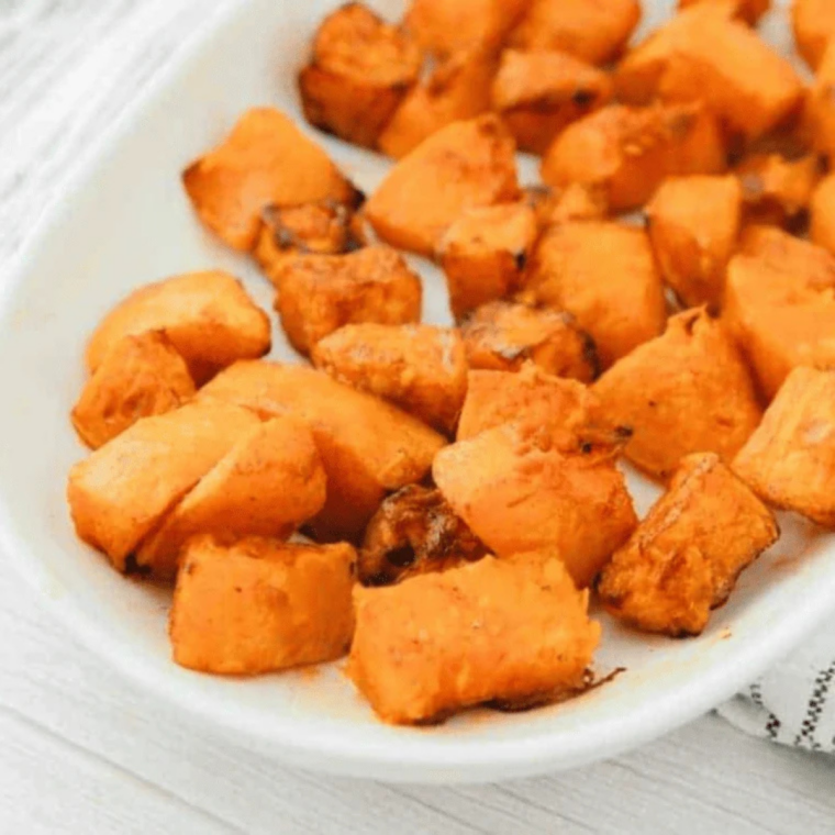 Air fryer frozen butternut squash cubes with caramelized golden edges in a white serving bowl