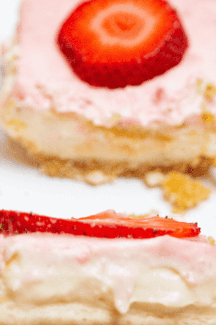 Air Fryer Strawberry Cheesecake Bars with golden crust, creamy cheesecake filling, and fresh strawberry topping, served on a white plate.