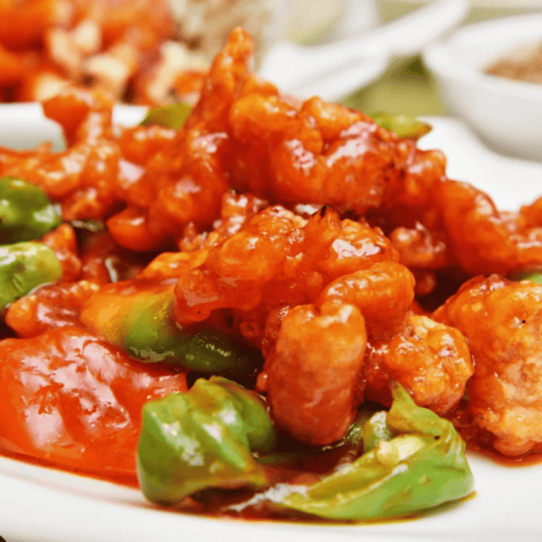 Golden crispy air fryer sweet and sour cauliflower served with sesame seeds and green onions