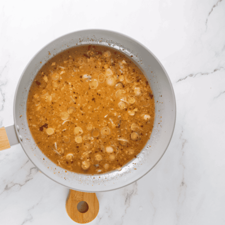 Whisking honey-orange glaze with garlic, ginger, and soy sauce in a bowl.