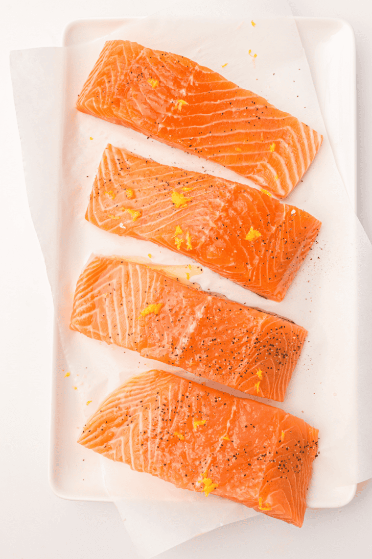 Salmon fillets coated in honey-orange glaze in a shallow dish before marinating.