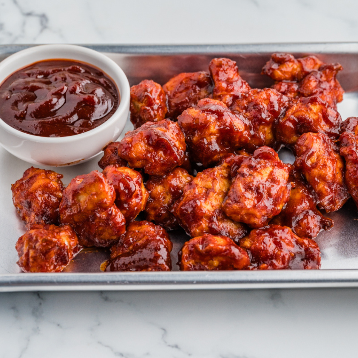 BBQ chicken bites on a plate with a bowl of homemade Heinz 57 sauce for dipping