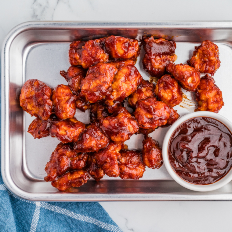 BBQ chicken bites on a wooden board with a small bowl of homemade Heinz 57 sauce
