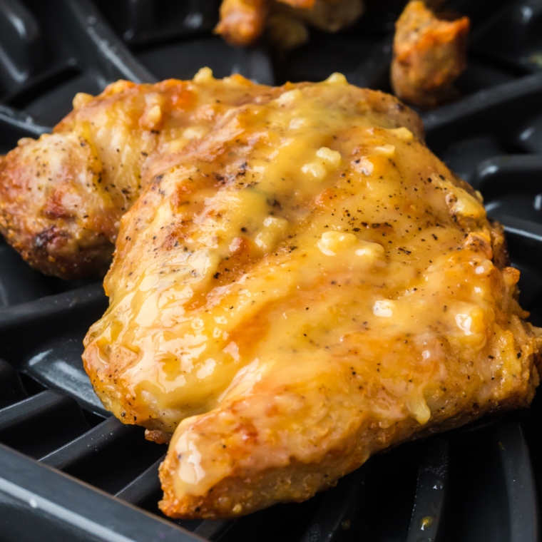 Carolina Gold BBQ sauce spooned over grilled chicken on a white plate