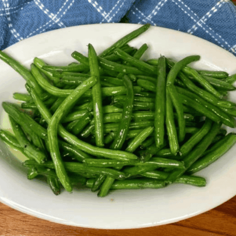 A bowl of tender Southern-style Bojangles green beans with bits of bacon and red peppers.
