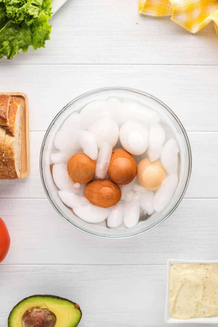 Peeled hard-boiled eggs cooling in an ice water bath
