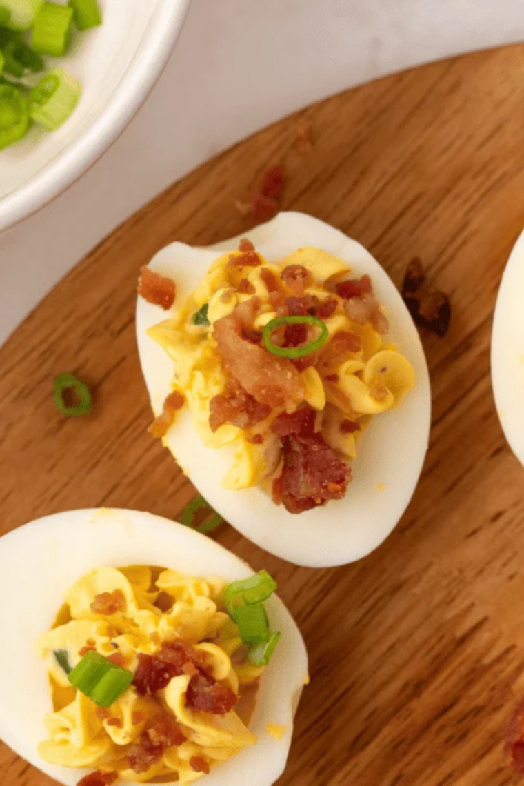Piping creamy filling into egg whites to make deviled eggs without mustard