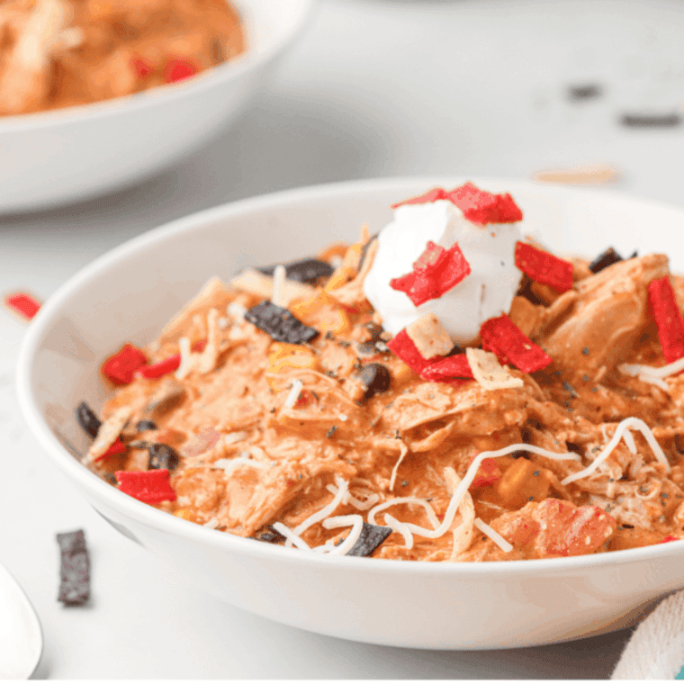 Bowl of Copycat Crockpot Jason’s Deli Chicken Chili with shredded chicken, beans, and garnished herbs.