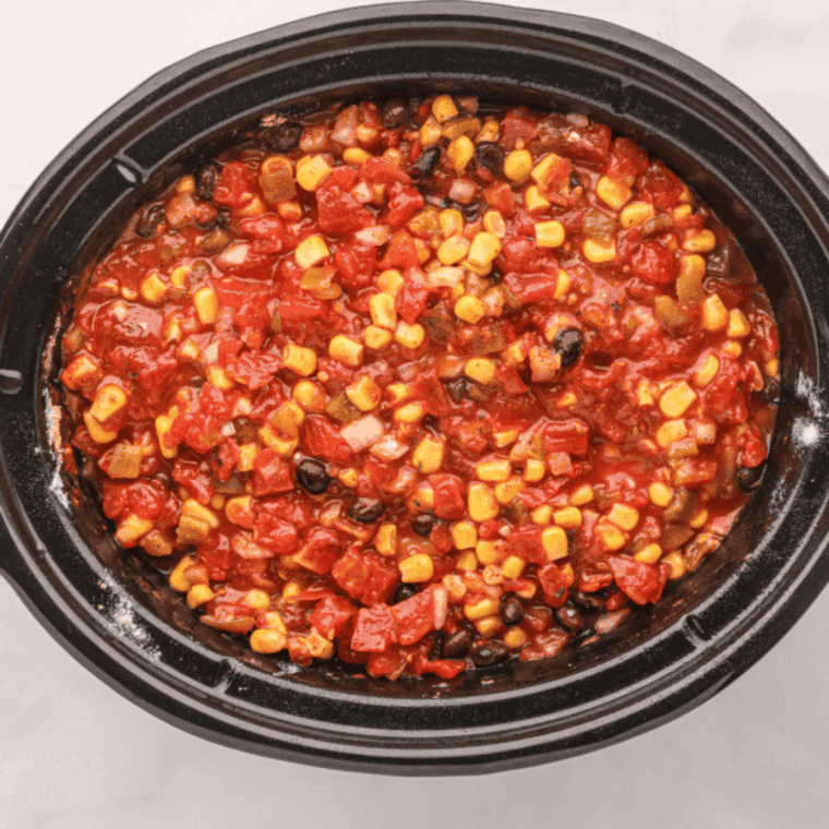 Shredding cooked chicken in a large bowl with forks before returning it to the crockpot and mixing.