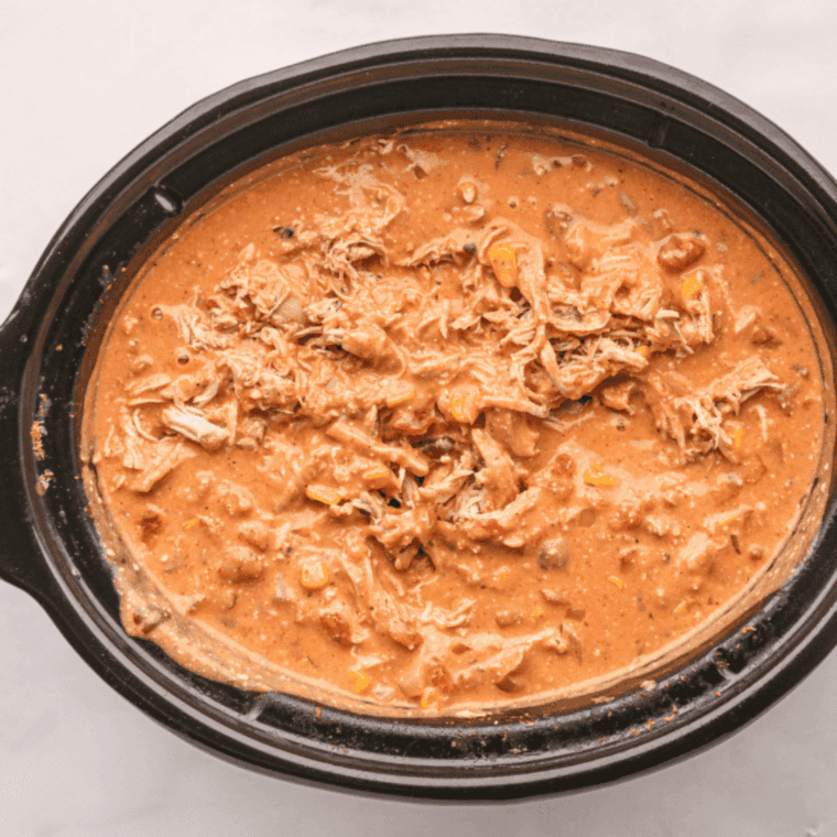 Bowl of chicken chili served with sour cream, shredded cheese, tortilla strips, and cilantro garnish.