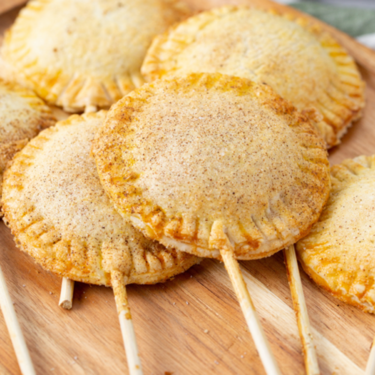 Air fryer apple pie pops with golden flaky pastry and cinnamon-spiced apple filling on sticks