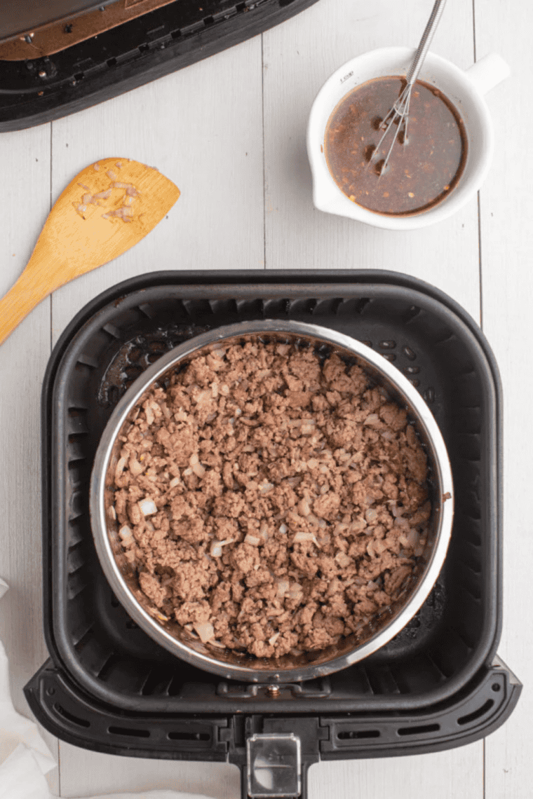 Cooked season ground beef in air fryer basket.