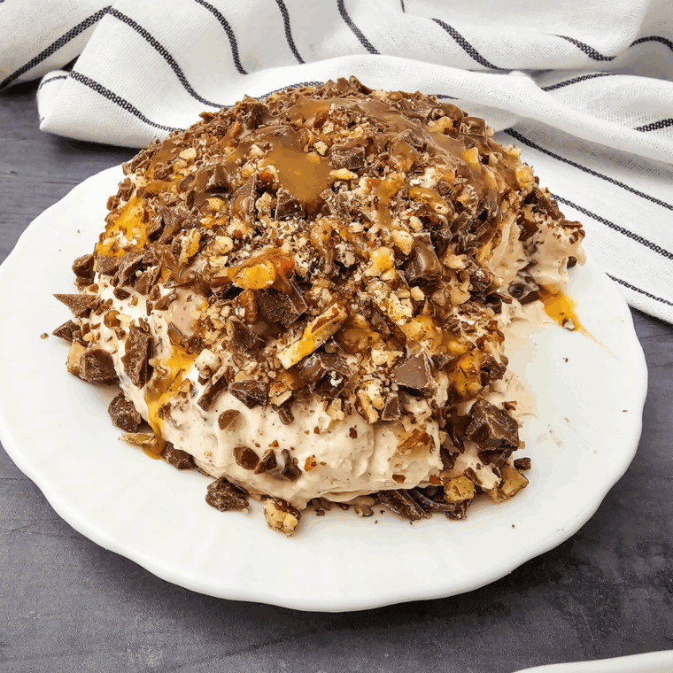 Easy Snickers Cheese Ball rolled in chopped peanuts, served on a platter with vanilla wafers and pretzels.