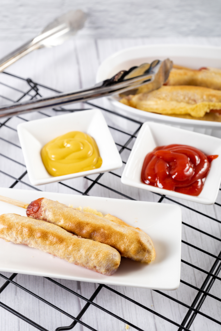 Homemade corn dogs cooked in the air fryer, served on a plate with wooden skewers.
