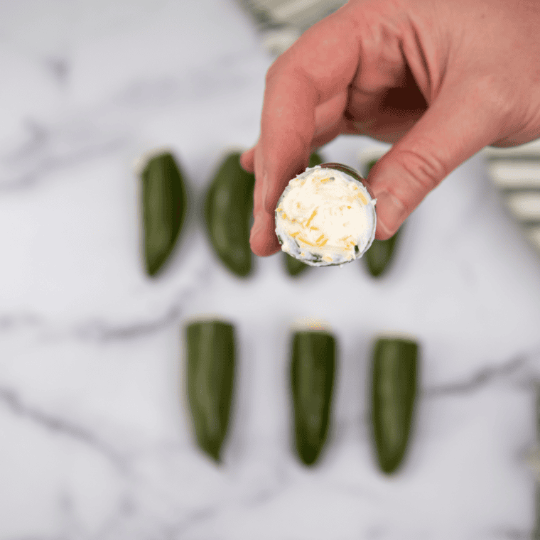 Jalapeños stuffed with cream cheese, wrapped in seasoned meat and bacon, secured with toothpicks.