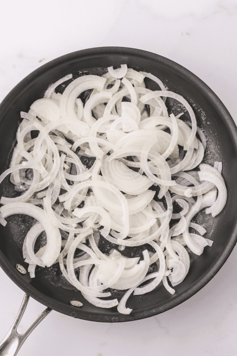 Sautéed onions cooking in butter in a small skillet.