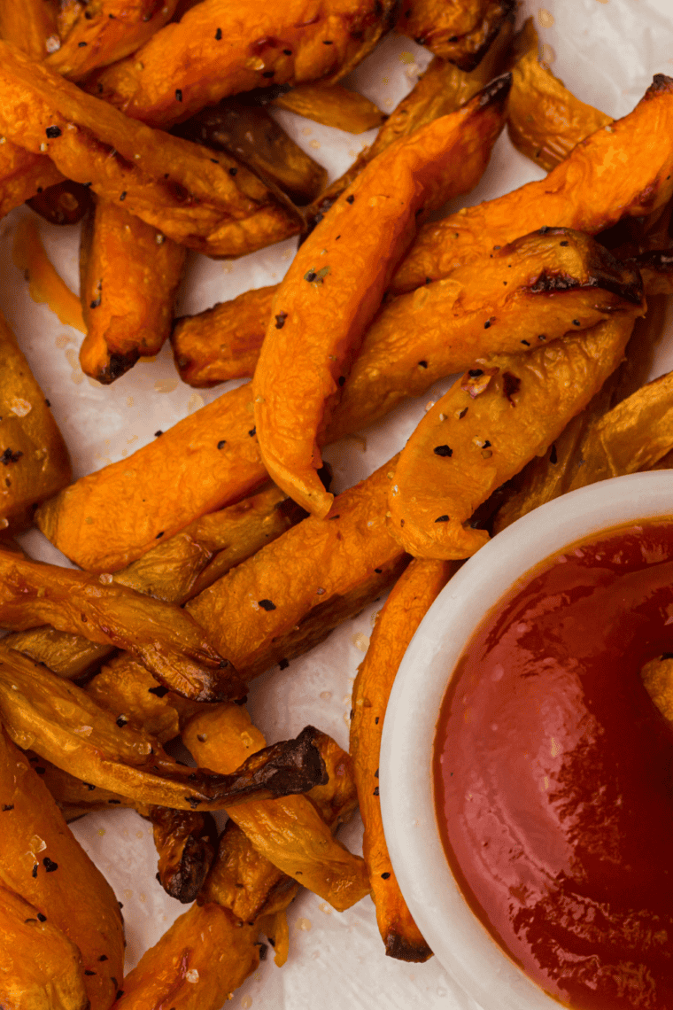 Golden, crispy sweet potato fries fresh from a Ninja Crispi air fryer, served on a plate.