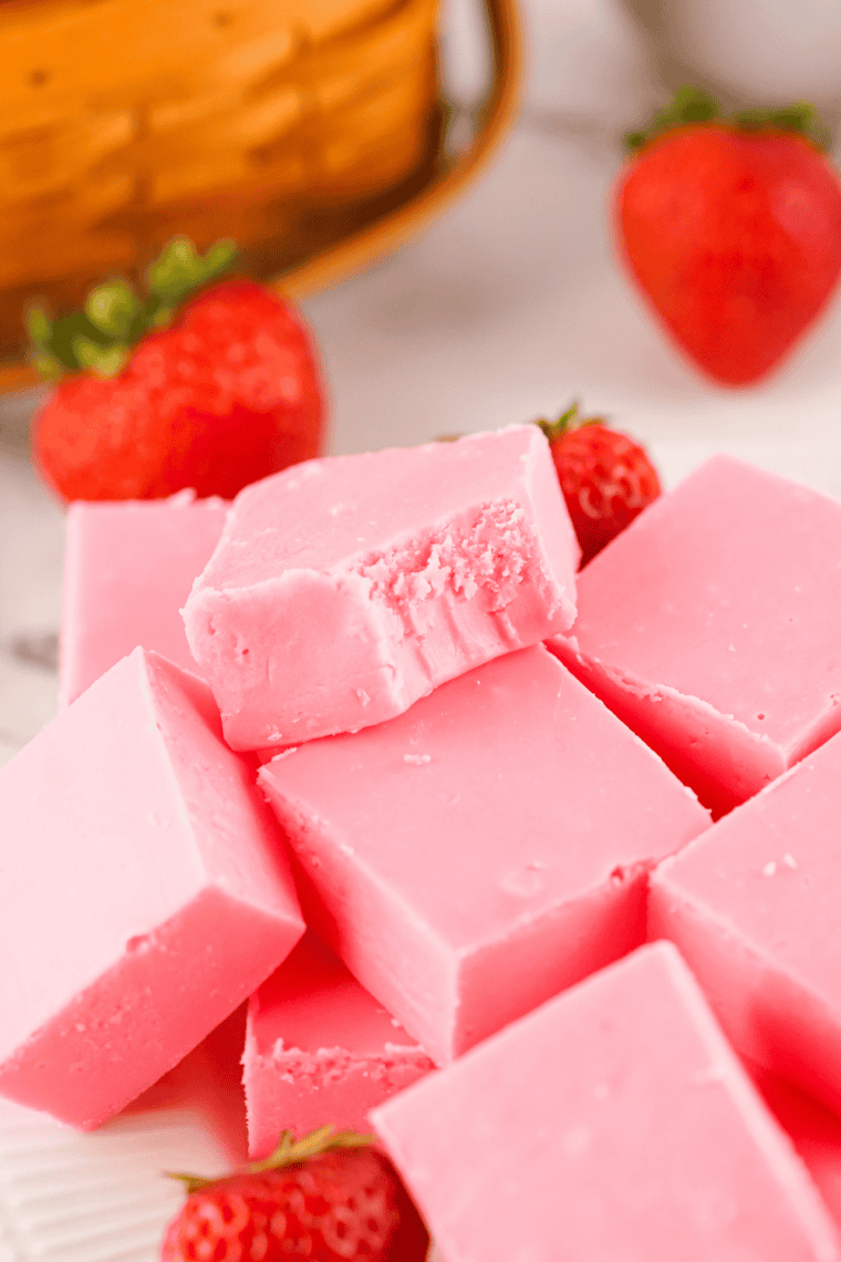 Stacked pieces of easy strawberry fudge showing creamy pink texture.