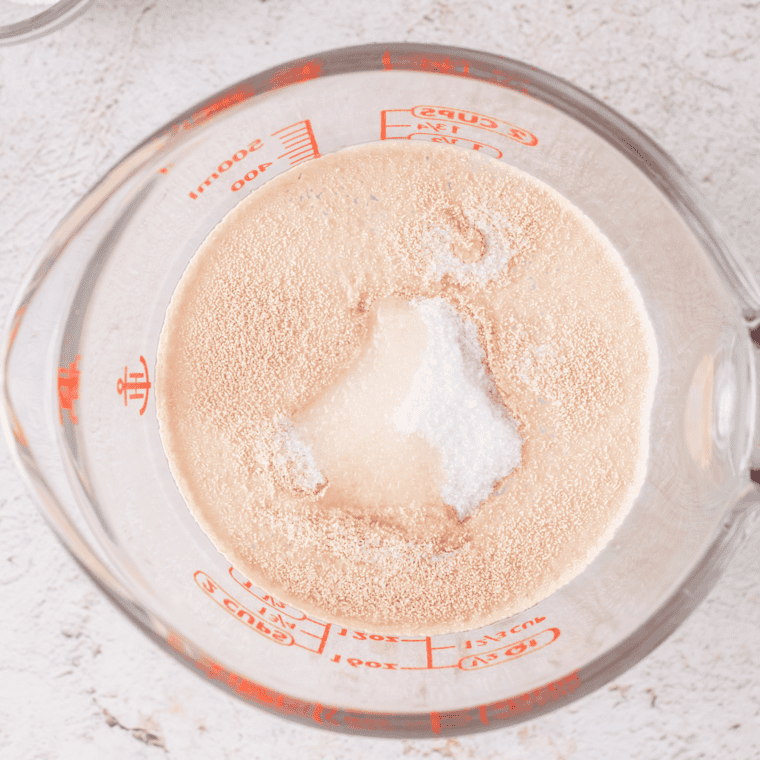 Foamy yeast proofing in a glass bowl of warm water with sugar