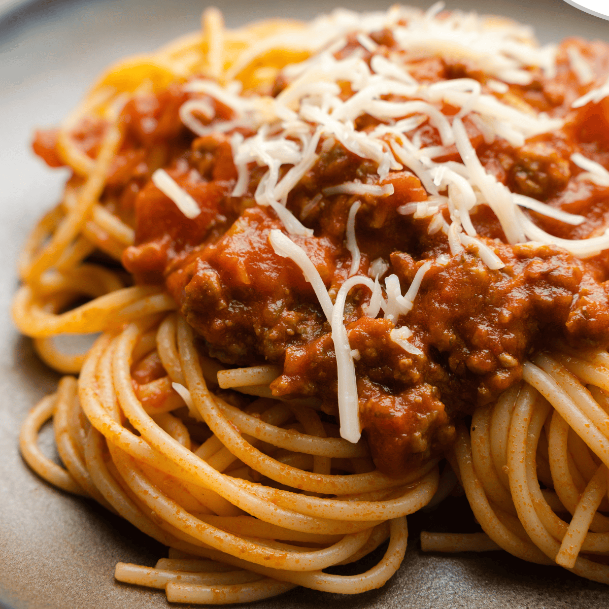 Bowl of Old Spaghetti Factory-style meat sauce over spaghetti noodles, garnished with herbs.