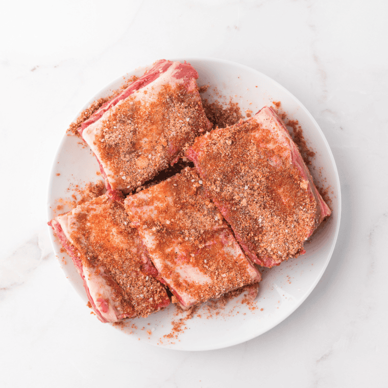 "Rubbing homemade Texas Roadhouse rib seasoning onto ribs before cooking for maximum flavor."