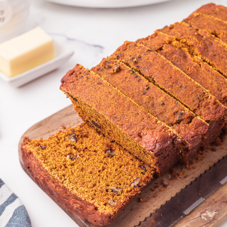 Slice of glazed pumpkin bread on a plate beside a cup of coffee
