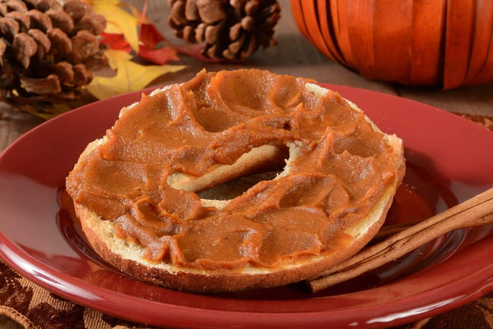 Pumpkin butter spread on a cinnamon bagel with cinnamon sticks