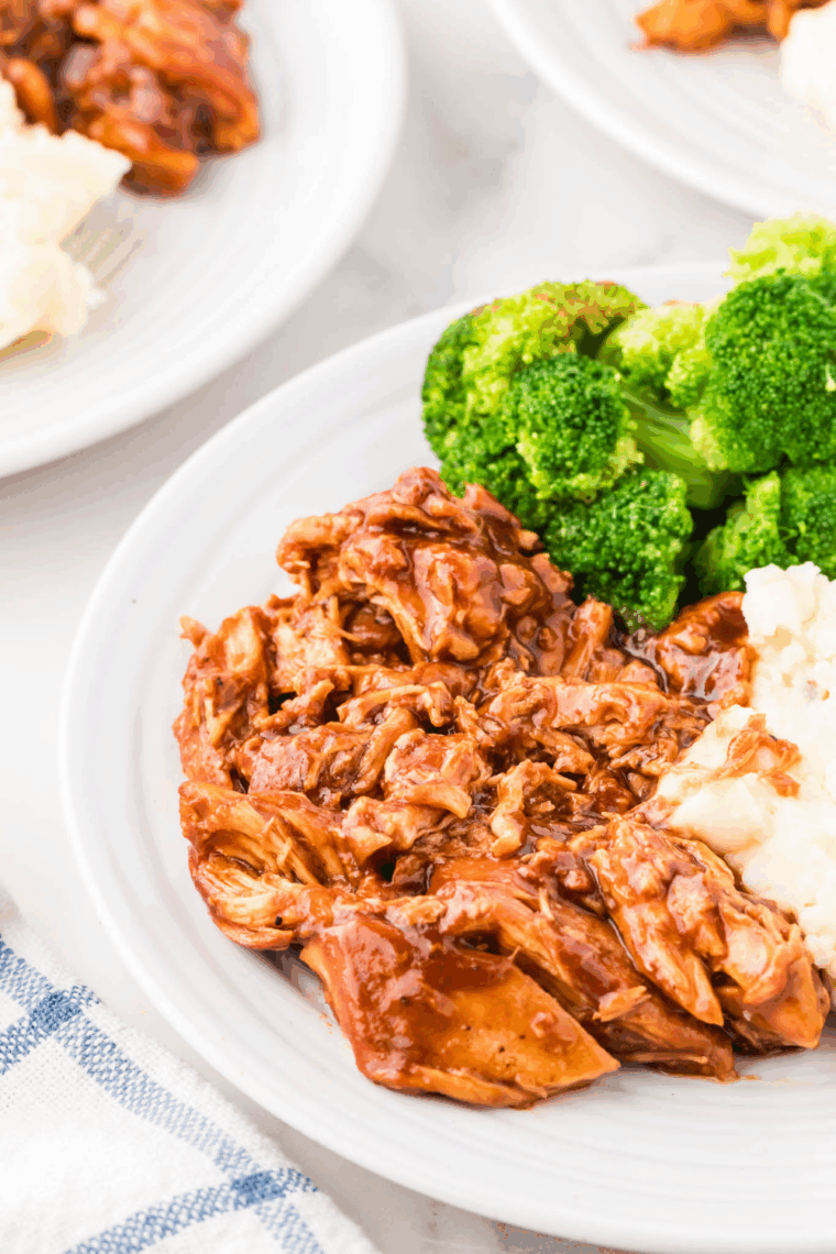 Crock Pot BBQ pulled chicken plated with steamed rice and broccoli for an easy dinner.