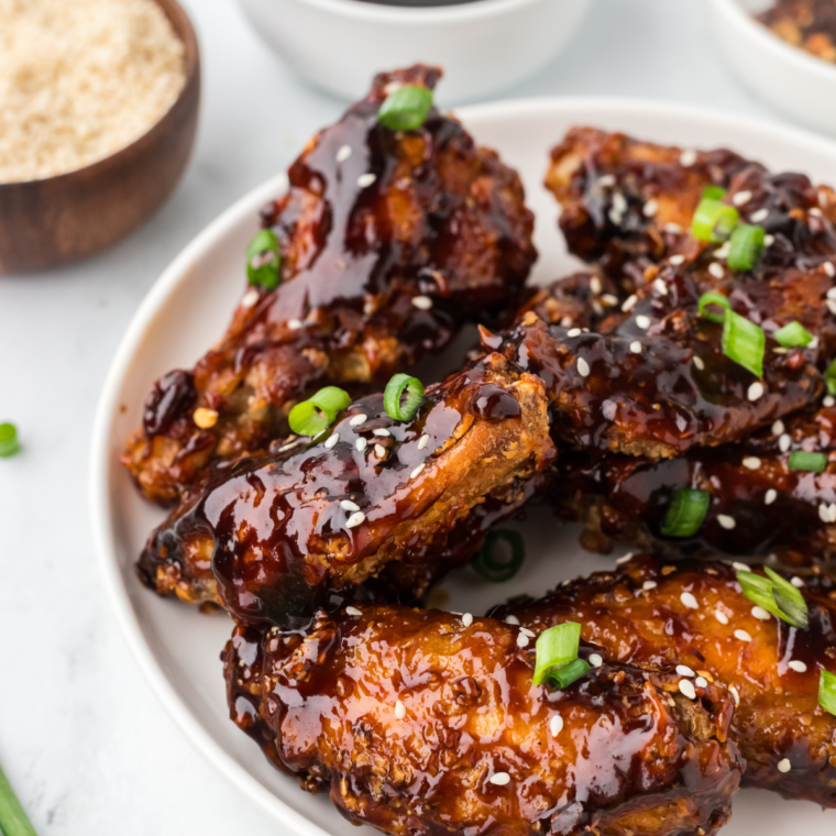 Air fryer Chinese chicken wings garnished with chopped green onions on a white plate.