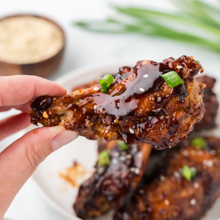 Plated air fryer Chinese chicken wings sprinkled with sesame seeds and sliced scallions.