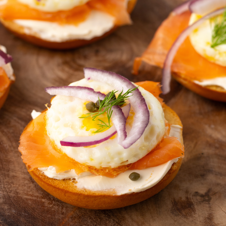Bagel with cream cheese, lox and red onions, on a cutting board.