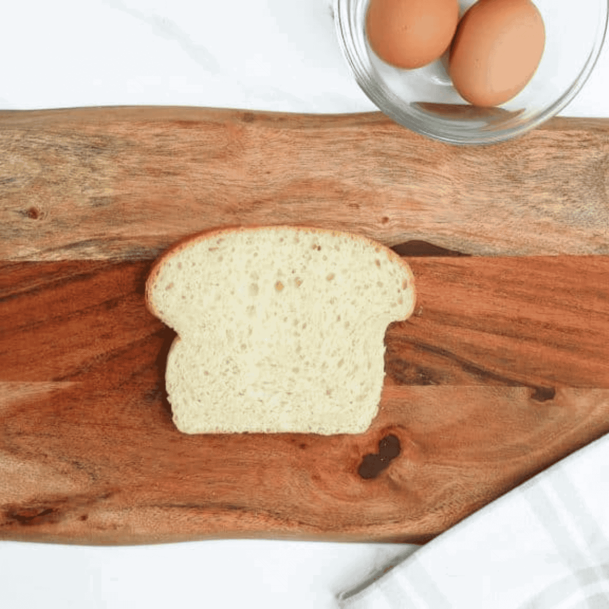 Spraying air fryer-safe pan with non-stick spray and placing bread slice in the air fryer basket.