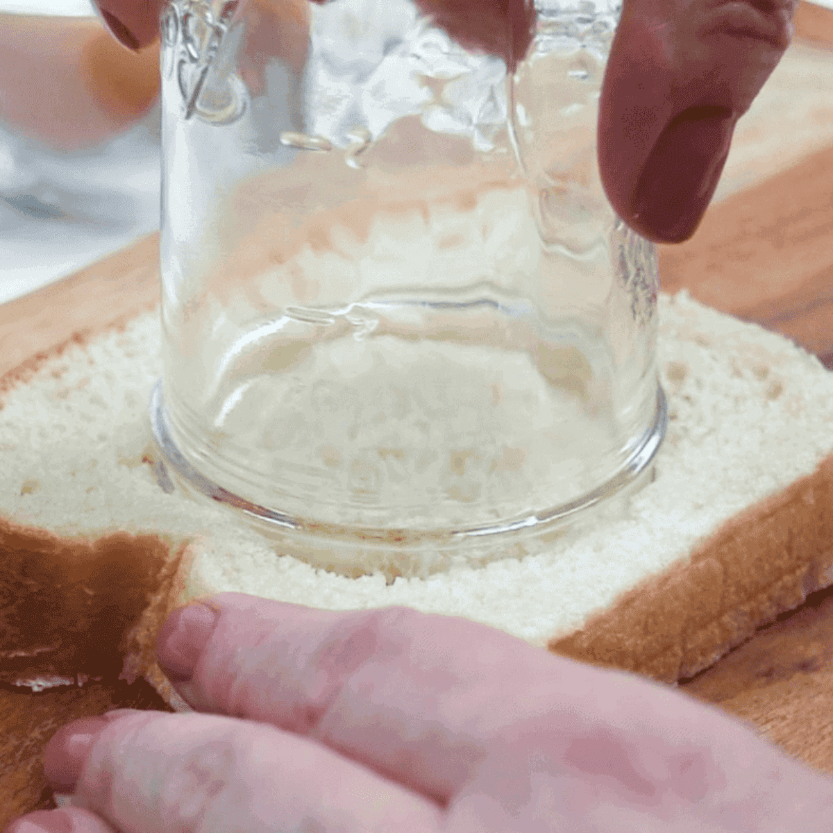 Using a cup or cookie cutter to make a hole in the bread and removing the cut-out piece.