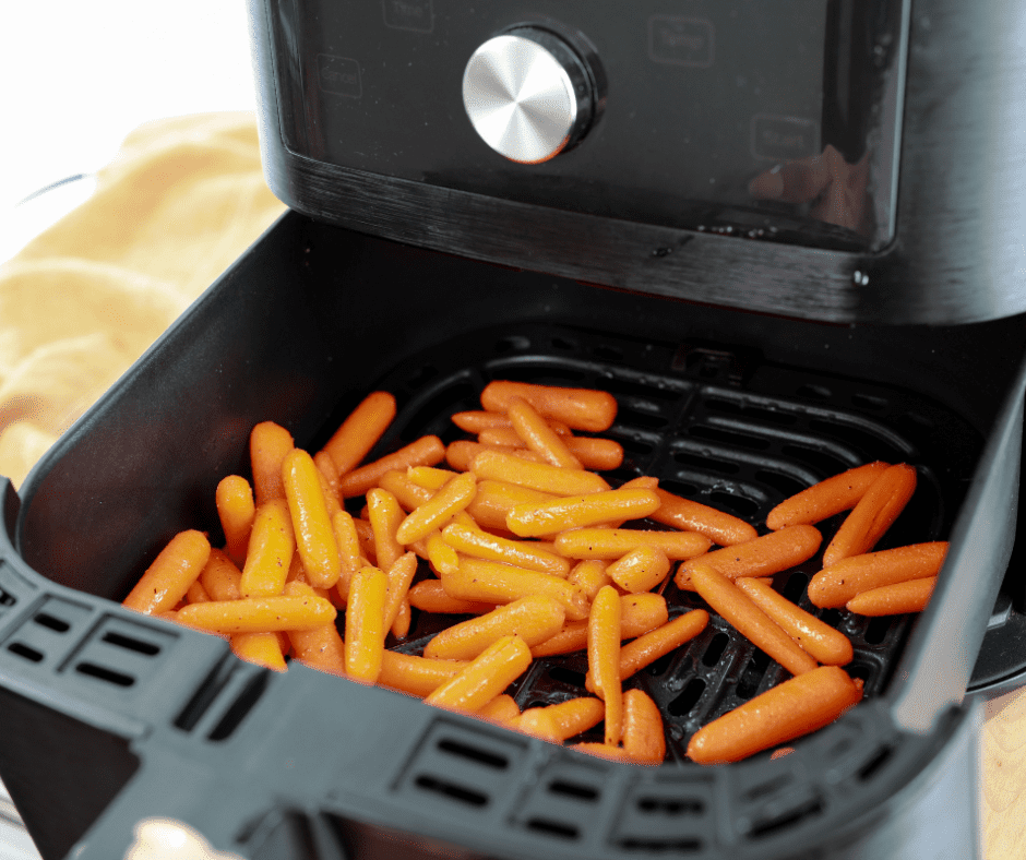 Seasoned baby carrots arranged in a single layer in the air fryer basket.