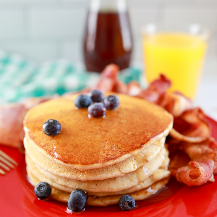 Air fryer pancakes served with syrup and fresh berries on plate