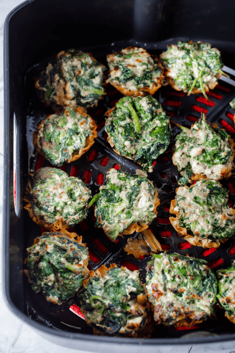 Air fryer spanakopita phyllo cups filled with spinach and feta, crispy and golden on a serving plate.