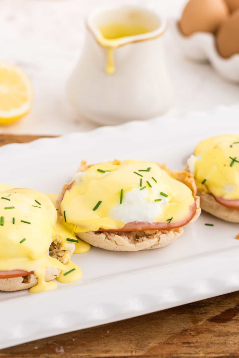 Easy air fryer eggs benedict with ham, poached eggs, and hollandaise on toasted English muffins.
