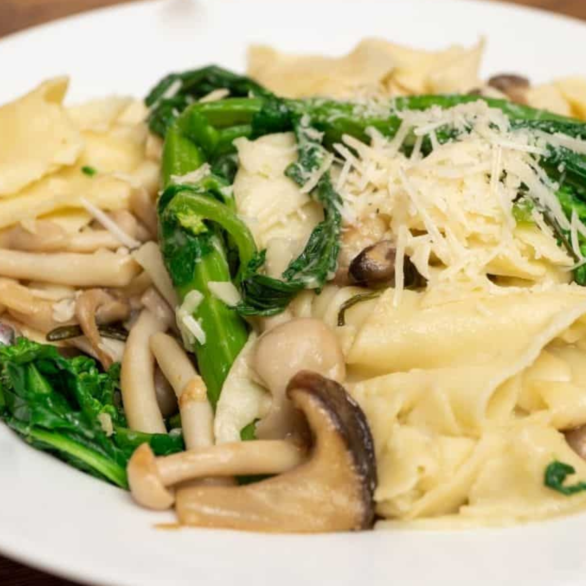 "Plate of Instant Pot Penne pasta tossed with sausage and broccoli rabe, garnished with Parmesan cheese."