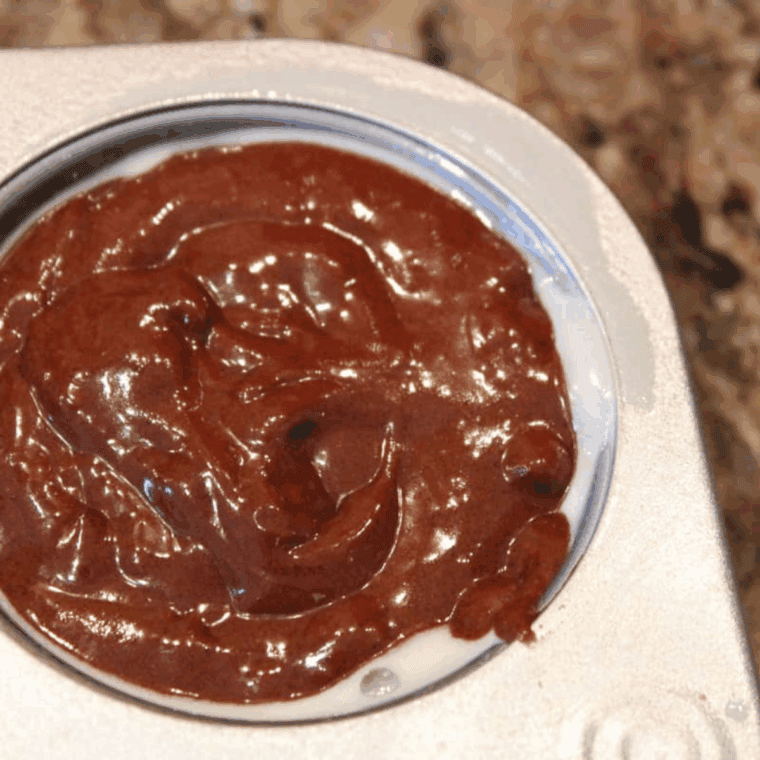 Filling greased muffin cups with chocolate muffin batter