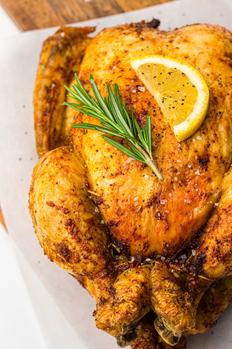 Golden whole chicken with crispy skin in air fryer basket