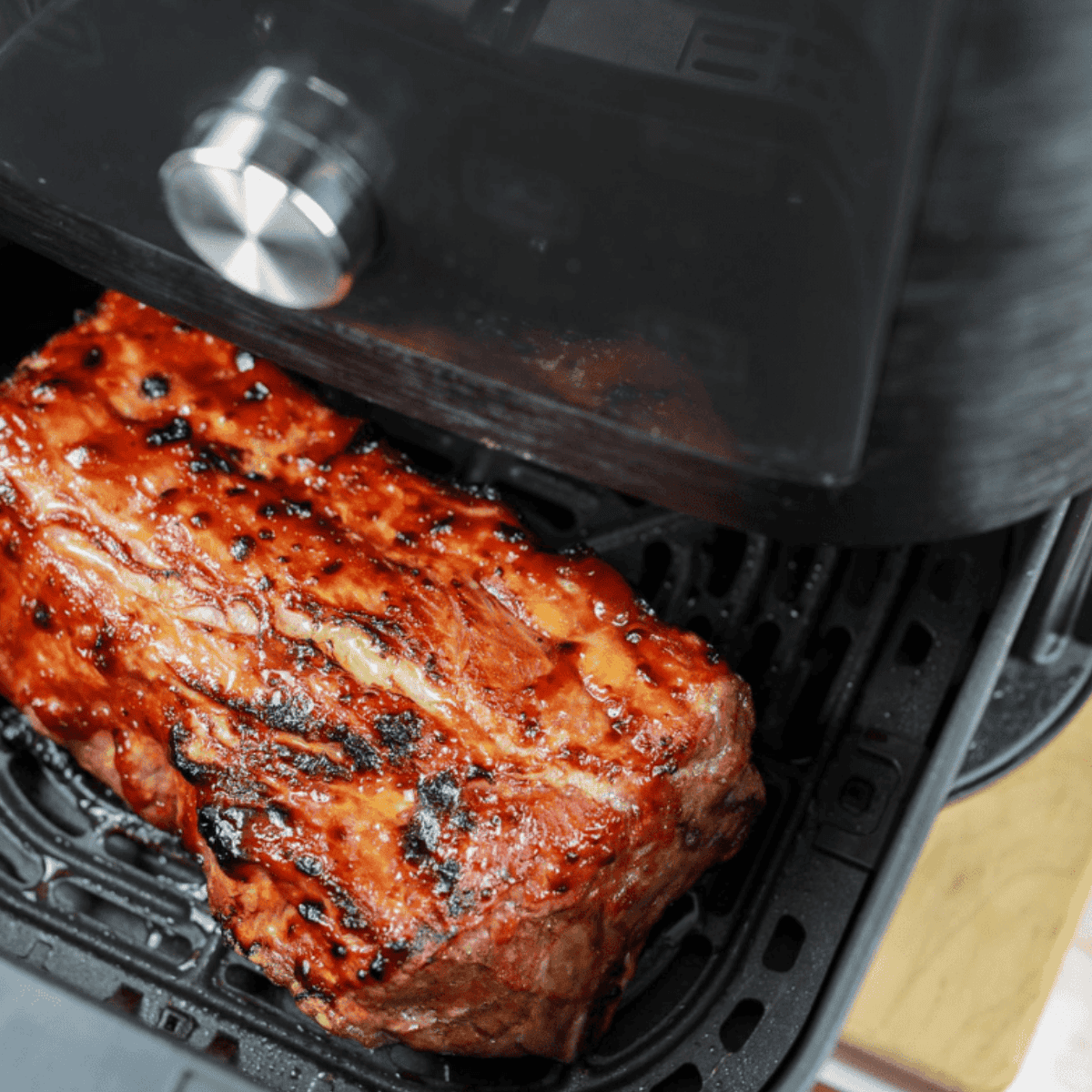 Ribs placed in air fryer, flipped halfway through, and brushed with BBQ sauce.
