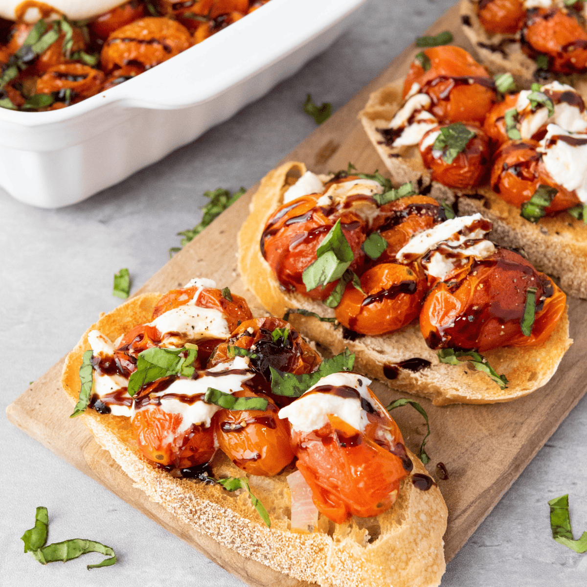 Copycat Cheesecake Factory Bruschetta topped with tomatoes, basil, and balsamic glaze on toasted baguette slices.