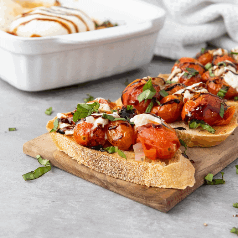 Homemade copycat Cheesecake Factory bruschetta topped with tomatoes, burrata, and balsamic glaze on toasted baguette slices.